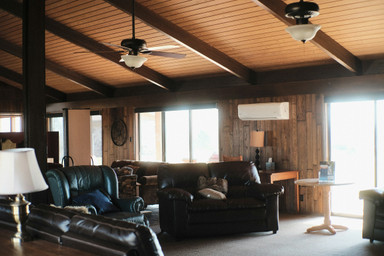 A big room in a large ranch house, where a circle of black leather couches faces the television