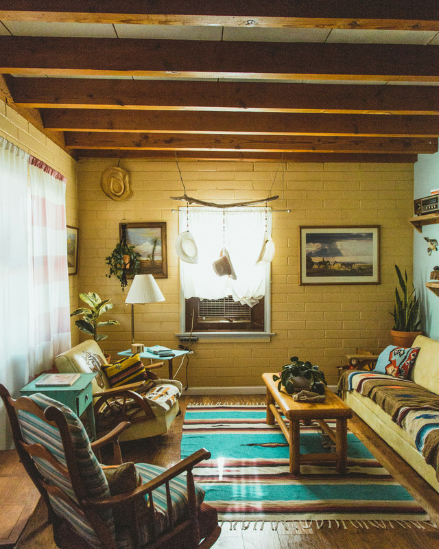 A yellow and blue southwestern style room, with a bright patterned native american rug and desert paintings